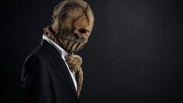 Fear and Halloween theme: a brutal killer in a mask on a dark background in the studio